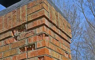 A chimney need repair due to missing mortar and broken bricks.